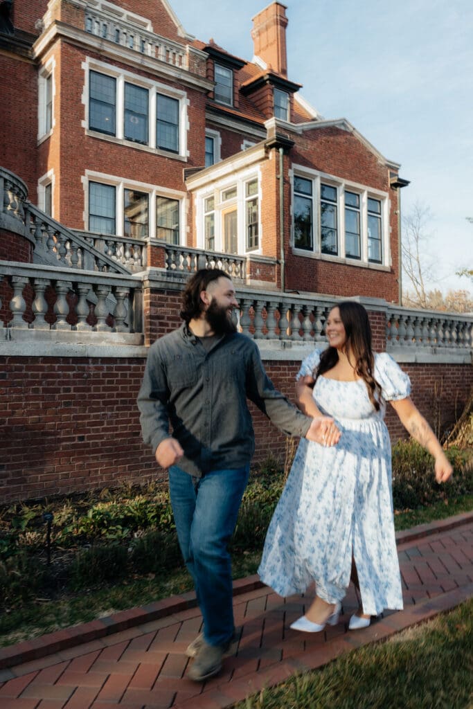 Bride-to-be and fiancé holding hands in front of Glensheen Mansion’s elegant architecture.