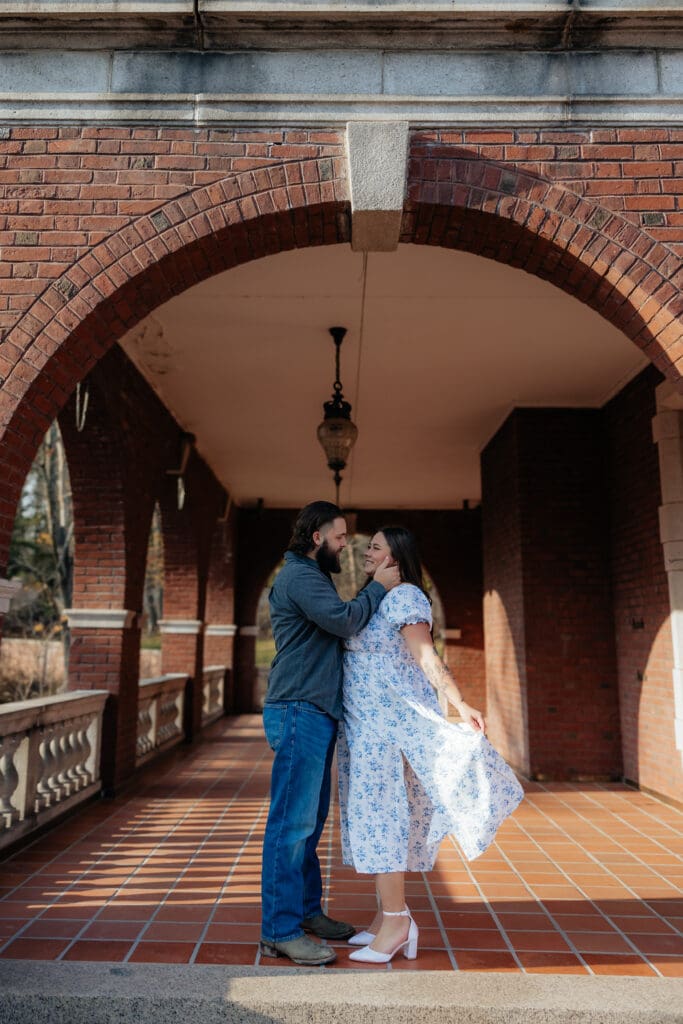 Romantic engagement photo of a couple sharing a kiss under the brick archways at Glensheen Mansion in Duluth, MN.