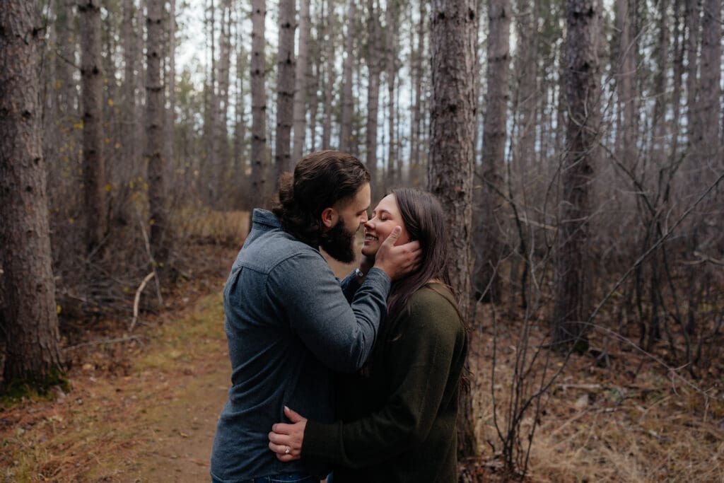 Romantic close-up of a couple holding each other, gazing into each other's eyes in the forest.