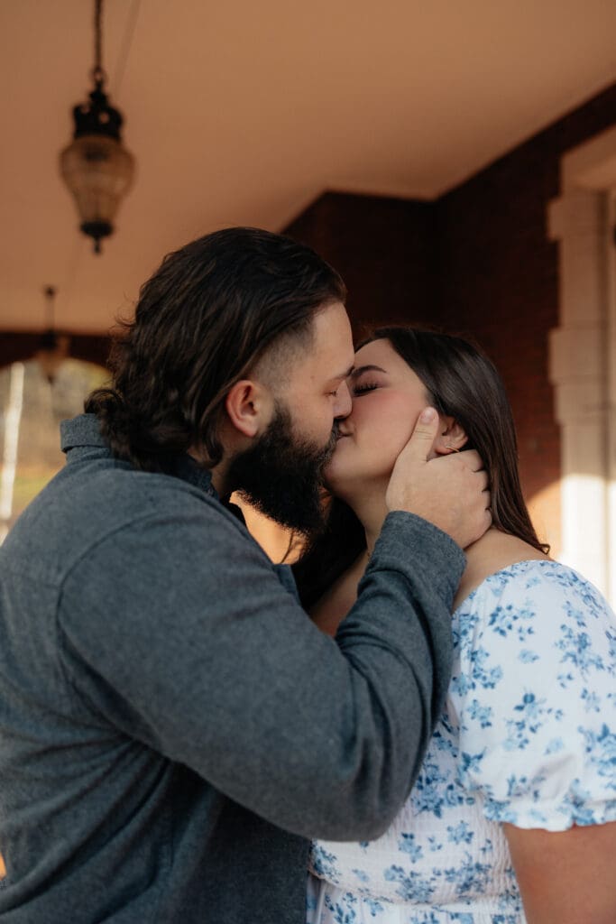 Engaged couple sharing a romantic kiss under the brick archways at Glensheen Mansion in Duluth, Minnesota.