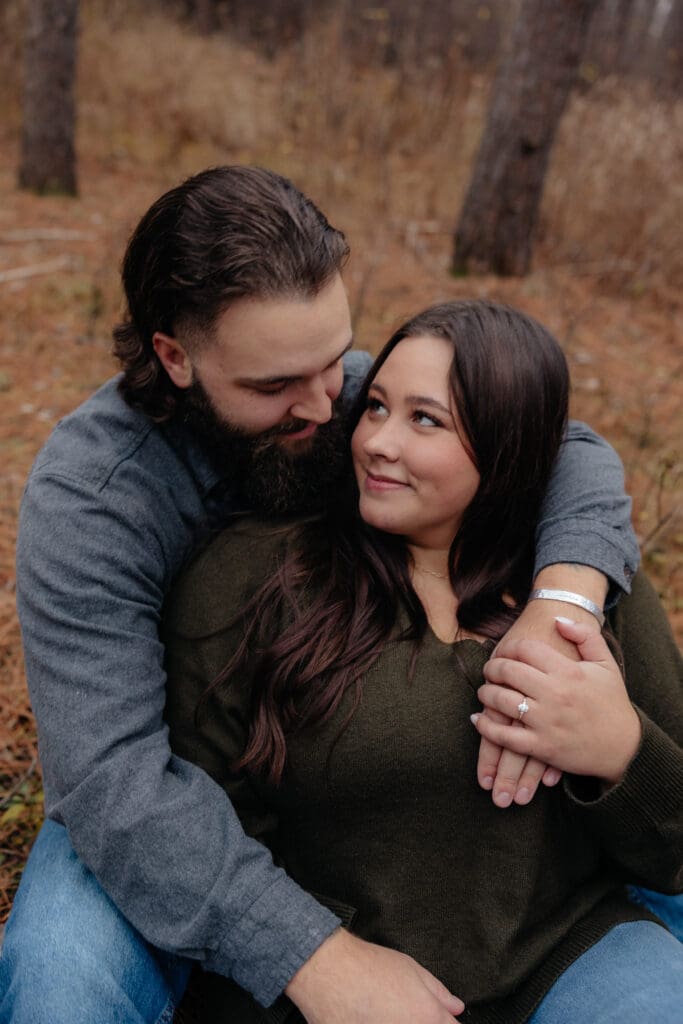 Couple sitting on the forest floor, wrapped in each other's arms and sharing a quiet moment.